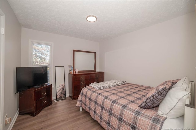 bedroom featuring a textured ceiling and light hardwood / wood-style floors