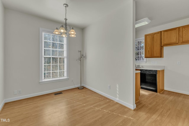 unfurnished dining area with a chandelier and light hardwood / wood-style floors