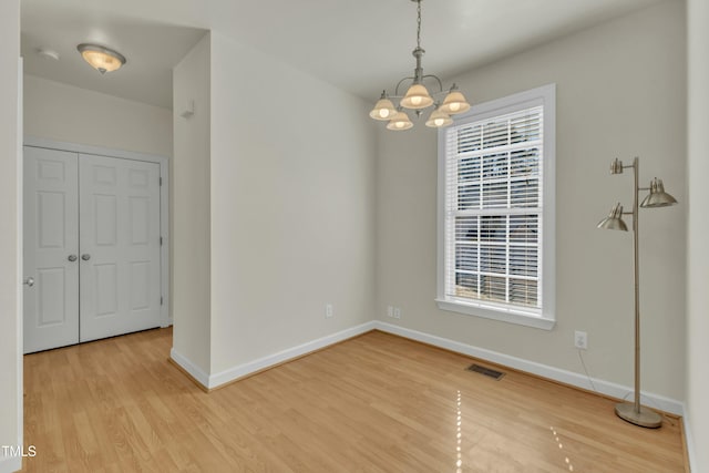 unfurnished room featuring a chandelier, light hardwood / wood-style flooring, and a wealth of natural light