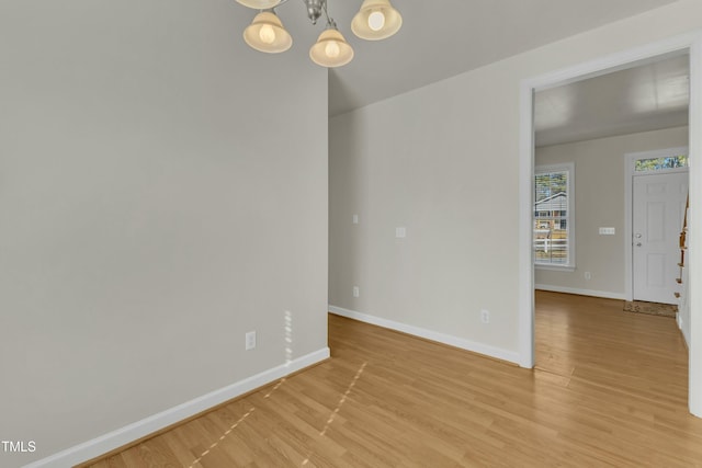 unfurnished room featuring an inviting chandelier and light hardwood / wood-style flooring