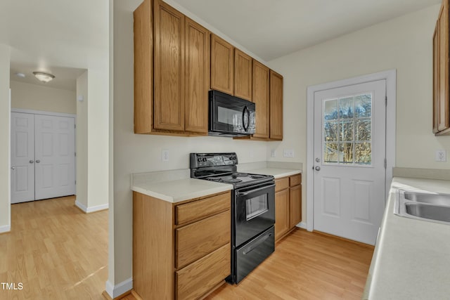 kitchen with sink, black appliances, and light wood-type flooring