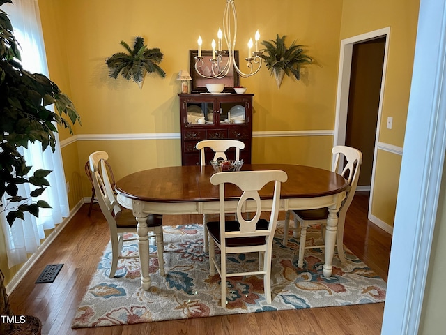 dining area with wood-type flooring and a notable chandelier