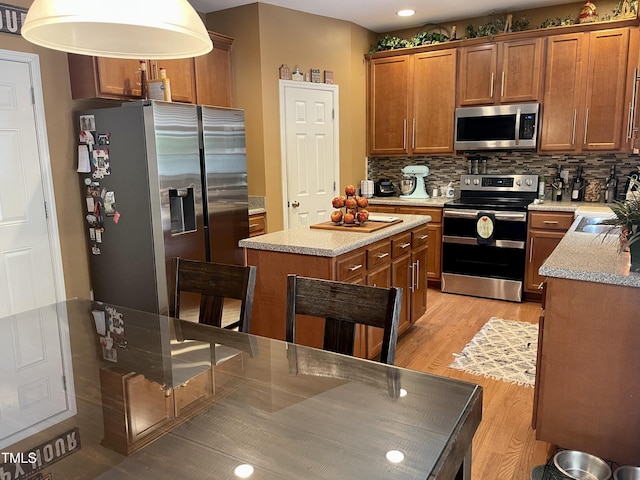 kitchen with stainless steel appliances, light wood-type flooring, a kitchen island, and backsplash