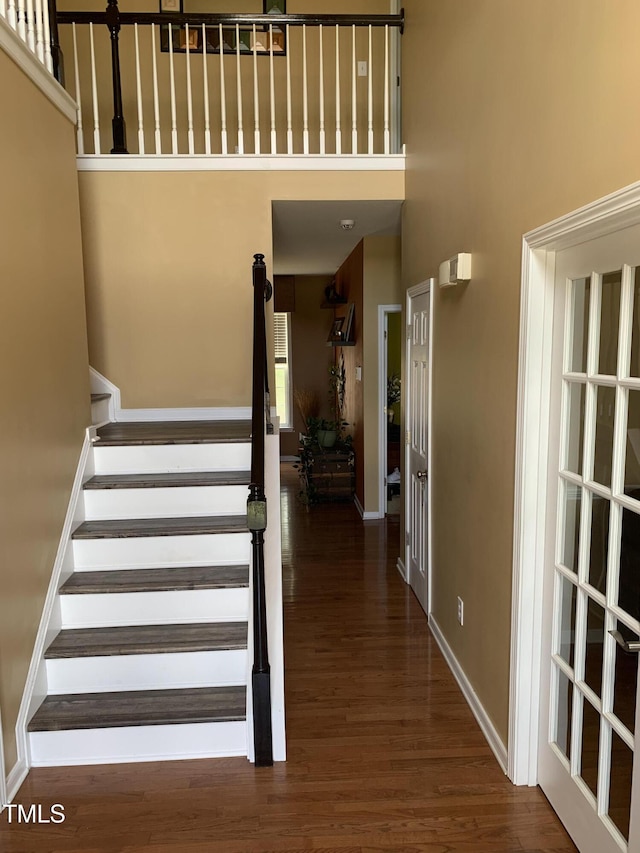 staircase with wood-type flooring and a high ceiling