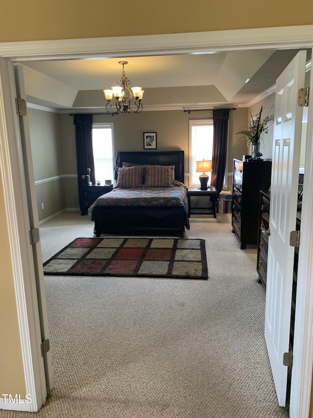 bedroom featuring an inviting chandelier, a tray ceiling, and light colored carpet