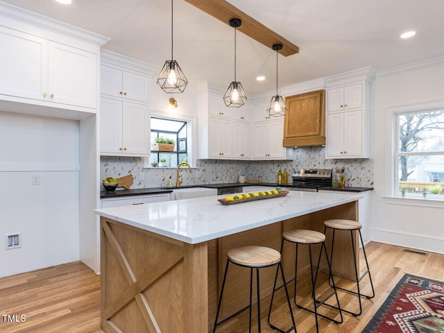 kitchen featuring white cabinetry, decorative backsplash, a center island, and stainless steel electric range oven