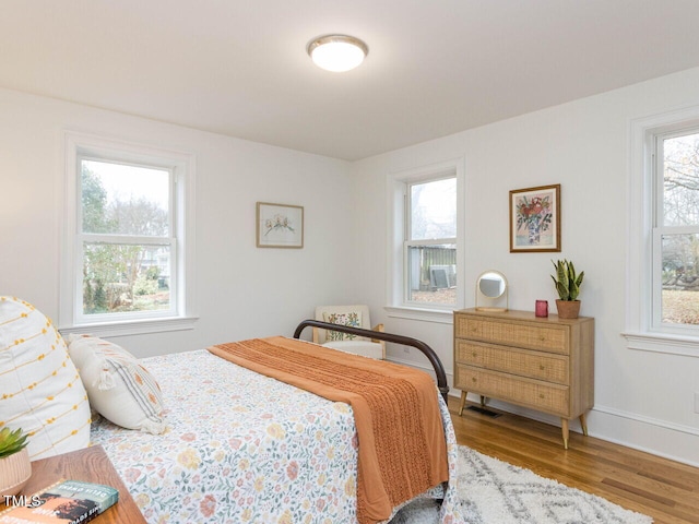 bedroom with hardwood / wood-style floors and multiple windows