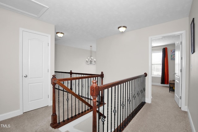 corridor featuring light colored carpet, a notable chandelier, and a textured ceiling