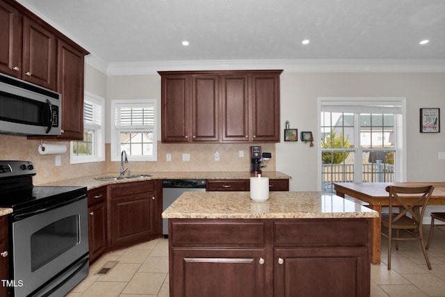 kitchen with sink, light stone counters, appliances with stainless steel finishes, a kitchen island, and backsplash