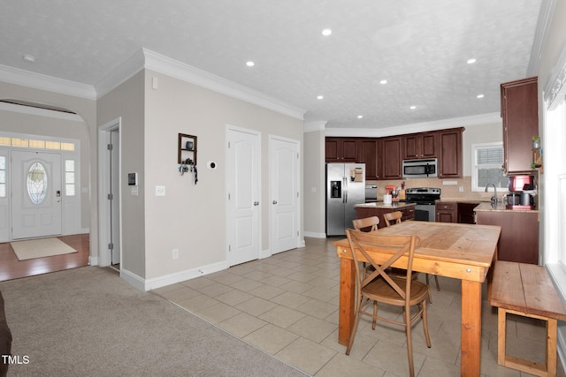 kitchen with appliances with stainless steel finishes, sink, ornamental molding, a center island, and dark brown cabinets