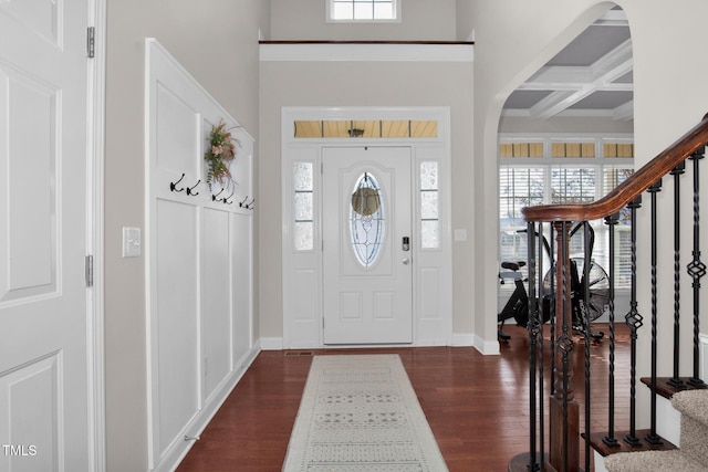 entrance foyer with beam ceiling, a high ceiling, coffered ceiling, and dark hardwood / wood-style floors