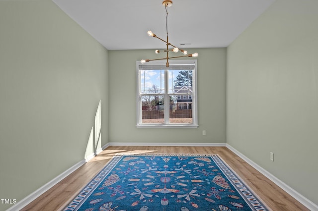 empty room featuring hardwood / wood-style floors and an inviting chandelier