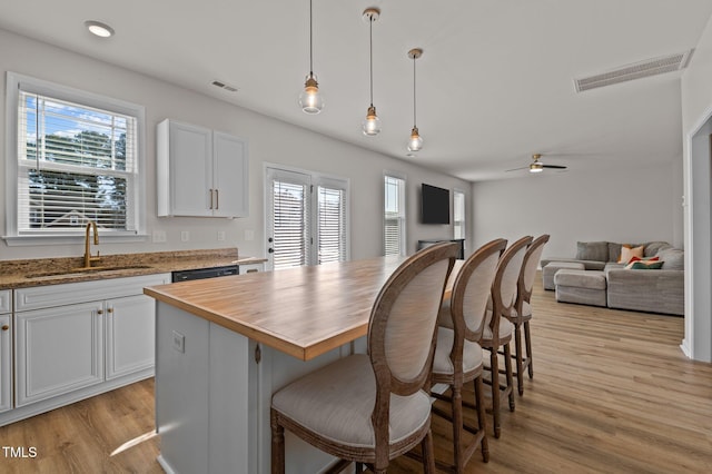 kitchen with hanging light fixtures, a kitchen island, sink, and white cabinets