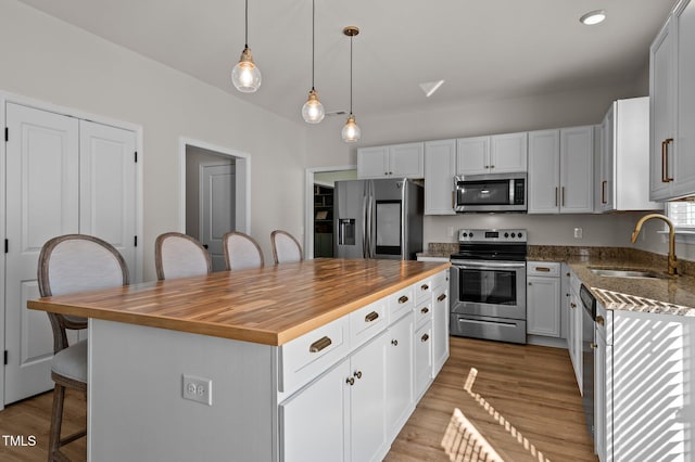 kitchen featuring a breakfast bar, sink, white cabinetry, a kitchen island, and stainless steel appliances