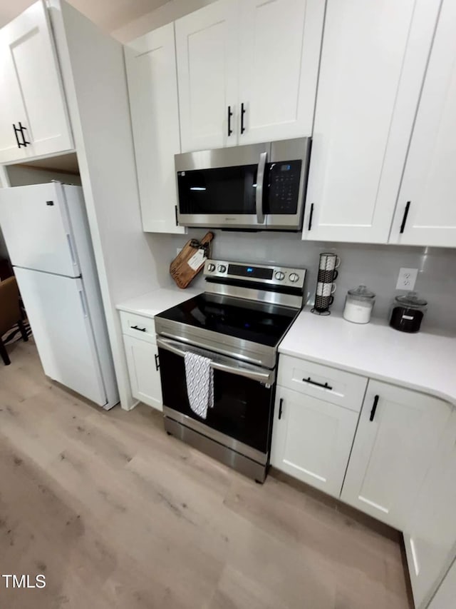 kitchen featuring stainless steel appliances, white cabinets, and light hardwood / wood-style flooring