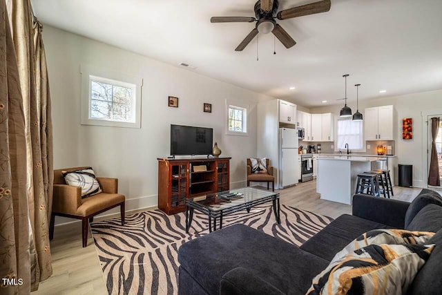 living room with sink, plenty of natural light, and light hardwood / wood-style floors