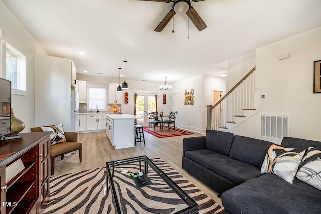 living room with sink, ceiling fan with notable chandelier, and light hardwood / wood-style floors