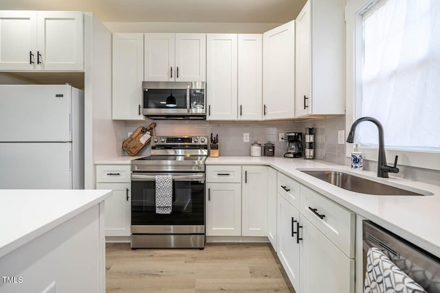 kitchen featuring sink, light hardwood / wood-style floors, white cabinets, and appliances with stainless steel finishes