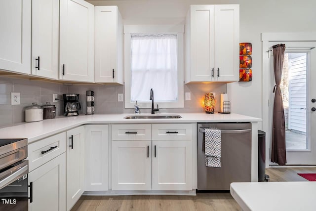 kitchen with sink, decorative backsplash, white cabinets, and dishwasher