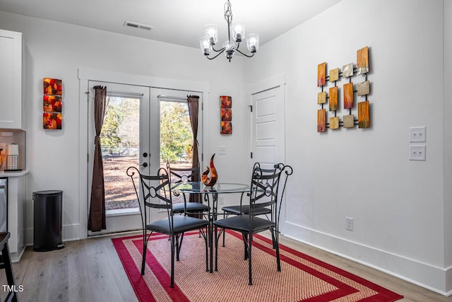 dining area featuring hardwood / wood-style floors, a notable chandelier, and french doors