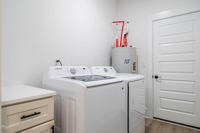 clothes washing area featuring light hardwood / wood-style floors, washer and clothes dryer, and electric water heater