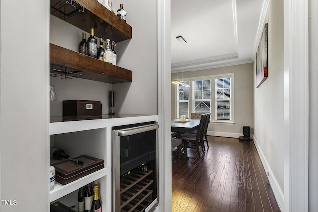 bar featuring dark hardwood / wood-style floors, ornamental molding, beverage cooler, and a raised ceiling