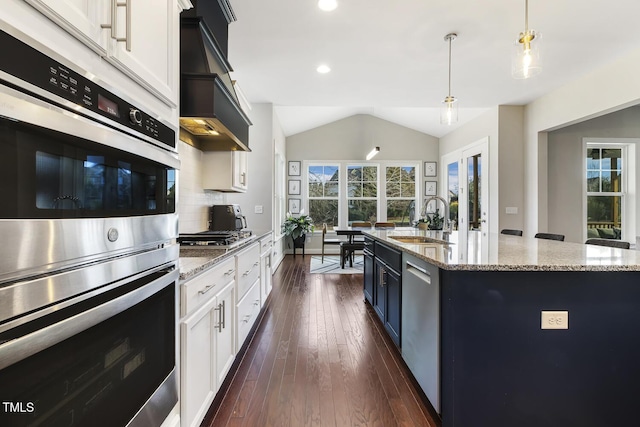 kitchen with stainless steel appliances, an island with sink, sink, and white cabinetry