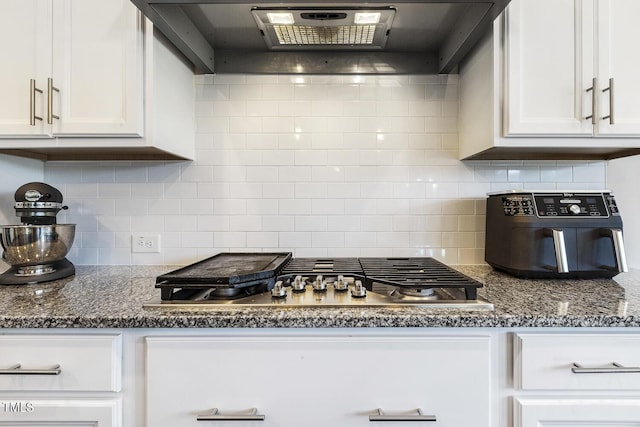 kitchen featuring white cabinetry, backsplash, stainless steel gas cooktop, dark stone counters, and wall chimney exhaust hood