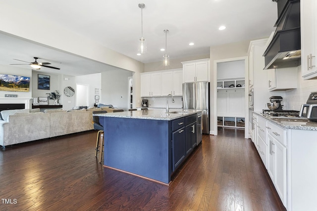 kitchen featuring pendant lighting, a center island with sink, white cabinets, blue cabinets, and custom exhaust hood