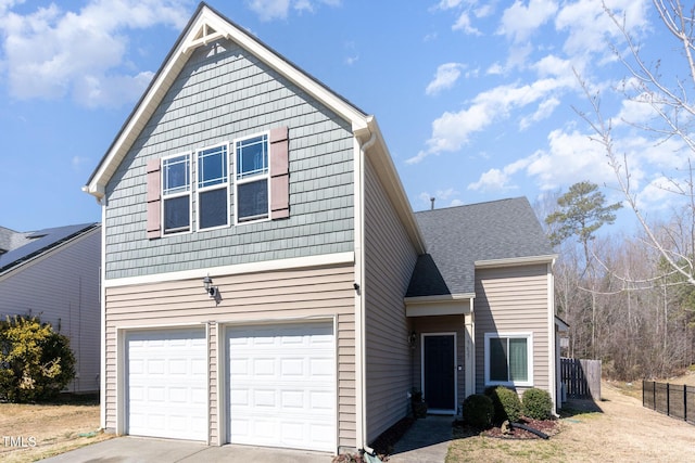 traditional-style home with a shingled roof, fence, driveway, and an attached garage