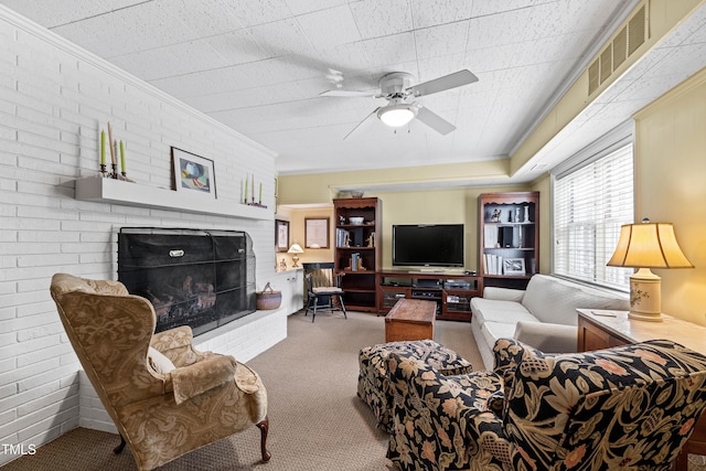 carpeted living room featuring crown molding, brick wall, ceiling fan, and a brick fireplace