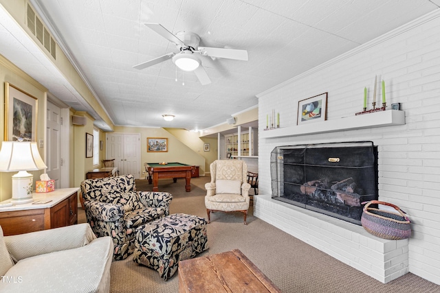 carpeted living room with crown molding, billiards, brick wall, and a brick fireplace