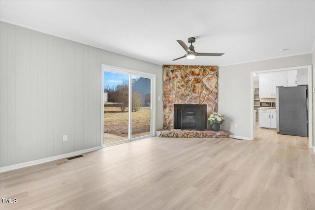 unfurnished living room with a fireplace, light hardwood / wood-style flooring, ornamental molding, and ceiling fan