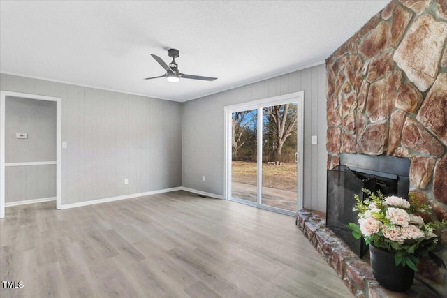 unfurnished living room featuring ceiling fan, a textured ceiling, a fireplace, and light wood-type flooring