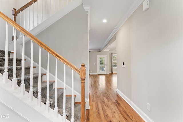 stairway with ornamental molding and wood-type flooring