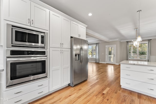 kitchen with white cabinetry, hanging light fixtures, stainless steel appliances, ornamental molding, and light wood-type flooring