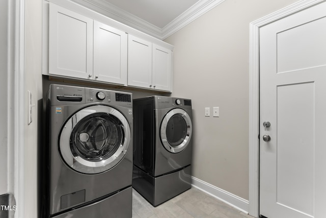 washroom featuring crown molding, washer and clothes dryer, and cabinets