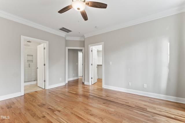 unfurnished bedroom with ensuite bathroom, crown molding, a spacious closet, a closet, and light hardwood / wood-style floors