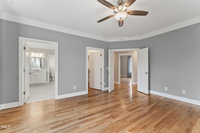 unfurnished bedroom with ornamental molding, a spacious closet, light wood-type flooring, and ensuite bath