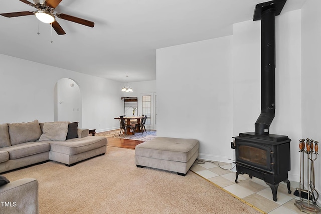 living room with tile patterned flooring, ceiling fan, and a wood stove