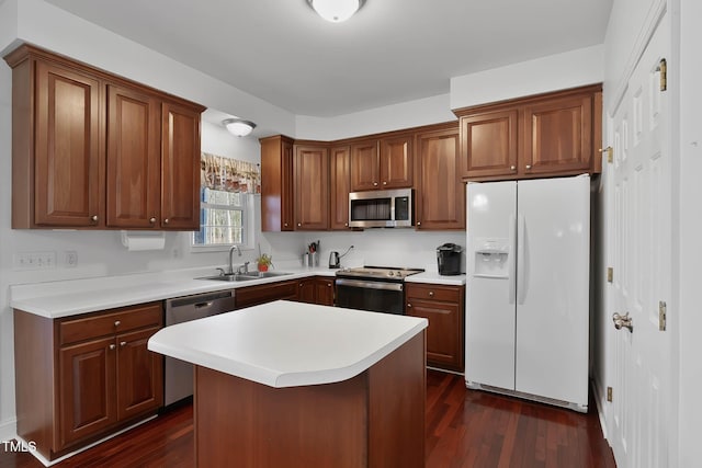 kitchen with appliances with stainless steel finishes, sink, a kitchen bar, a center island, and dark wood-type flooring