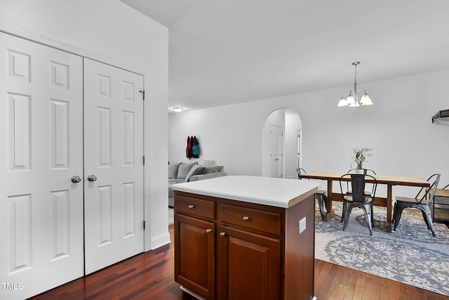 kitchen with a center island, pendant lighting, a notable chandelier, and dark wood-type flooring