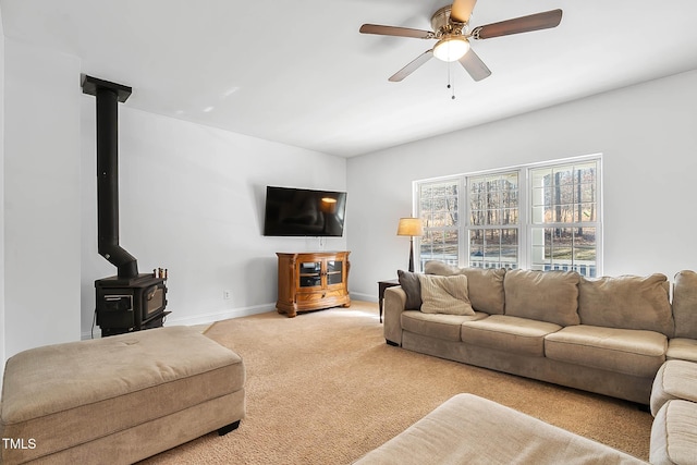 carpeted living room featuring a wood stove and ceiling fan