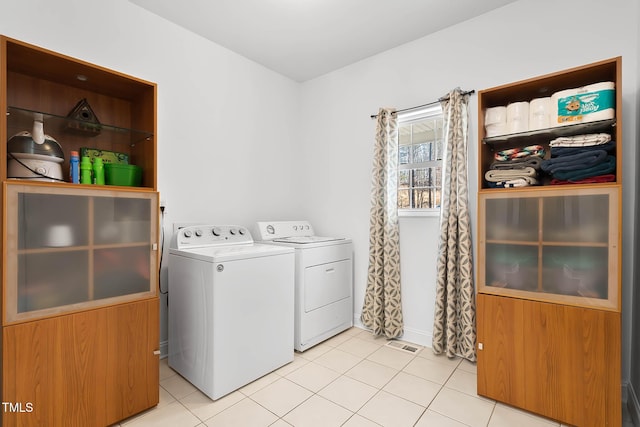 laundry area featuring washing machine and clothes dryer and light tile patterned flooring