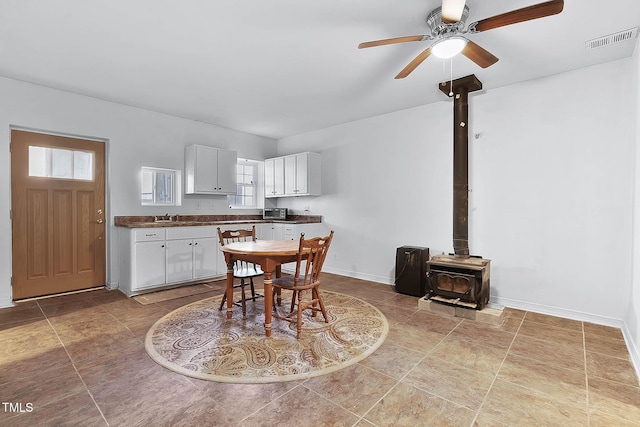 dining room featuring sink, ceiling fan, and a wood stove