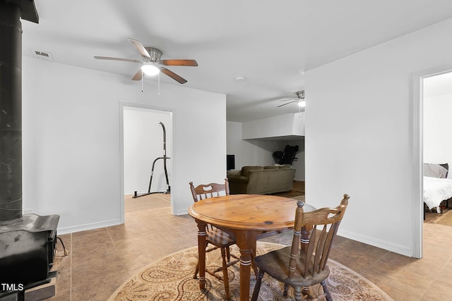 dining space featuring ceiling fan and a wood stove