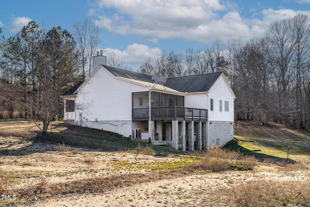 rear view of property featuring a wooden deck and a sunroom