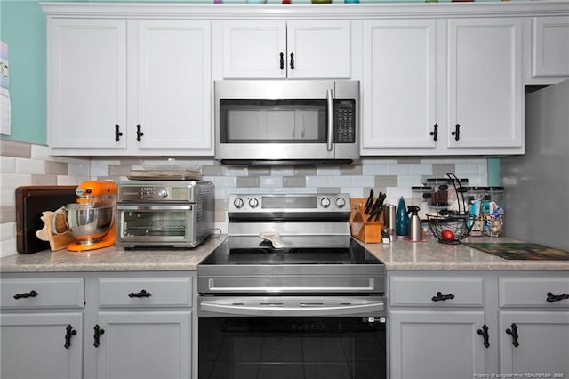 kitchen with tasteful backsplash, white cabinetry, and appliances with stainless steel finishes