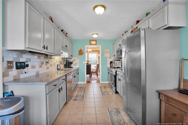 kitchen with sink, light tile patterned floors, backsplash, stainless steel appliances, and white cabinets