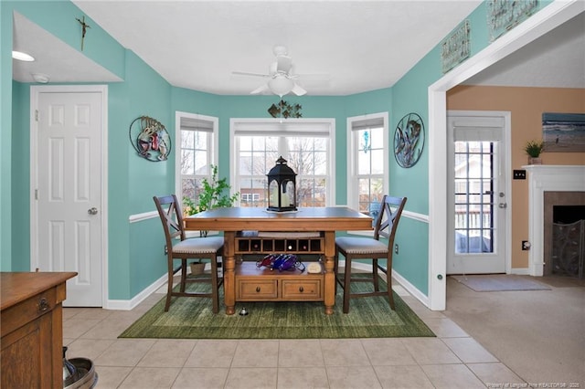 tiled dining area with ceiling fan, plenty of natural light, and a fireplace